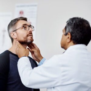 Doctor examining patient's neck in medical office.
