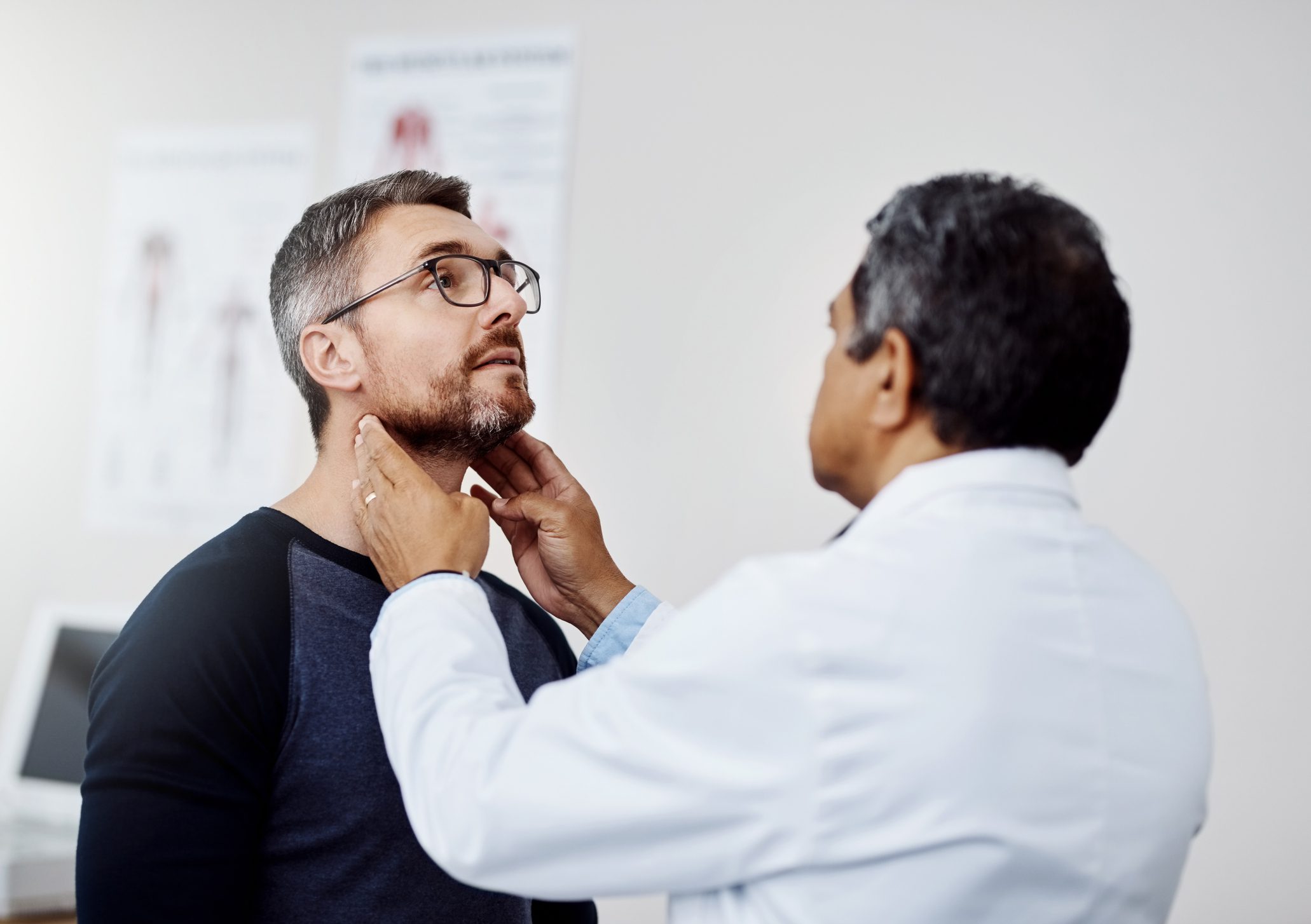 Doctor examining patient's neck in medical office.