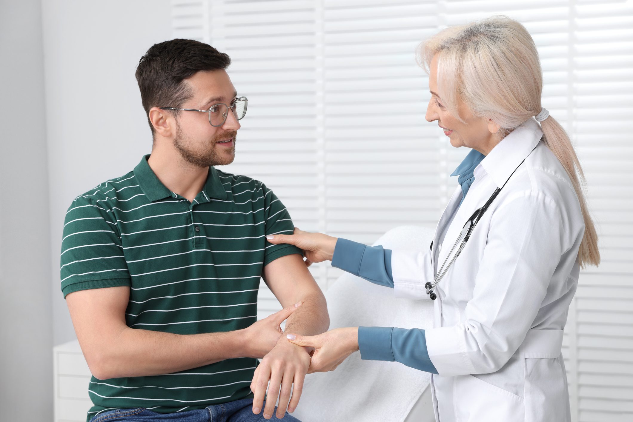 Doctor examining a patient's arm in clinic.